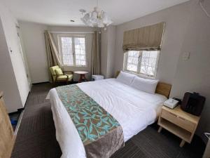 a bedroom with a large bed and two windows at Hakuba Sun Valley Hotel Annex - Vacation STAY 90337v in Iida