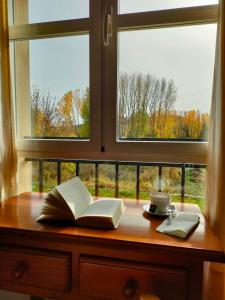 ein offenes Buch auf einem Holztisch neben einem Fenster in der Unterkunft Casa Rural Cuevas de Longarza 