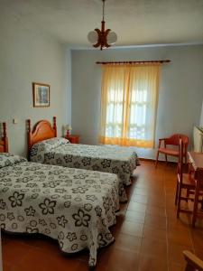 una camera d'albergo con tre letti e un tavolo con sedie di Casa Rural Cuevas de Longarza 