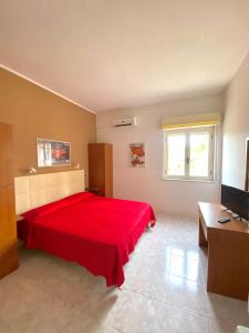 1 dormitorio con cama roja y TV en Residence Hotel Felix, en Ricadi