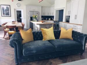 a black couch with yellow pillows in a kitchen at Gardeners Cottage at Balnakeilly Estate in Pitlochry