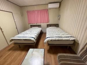 two beds in a small room with a table at Ryokan Warajisha - Vacation STAY 67784v in Goto