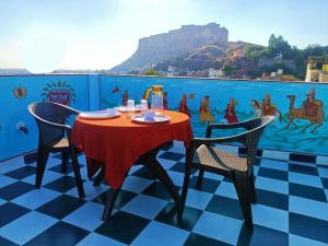 a table and chairs on a balcony with a painting on the wall at The Mehran way Homestay in Jodhpur