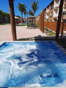 una piscina de agua azul junto a un edificio en Apart Resort Beira Mar Mutá - PS en Porto Seguro