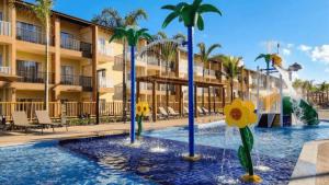 a pool at a resort with palm trees and a fountain at Apart Resort Beira Mar Mutá - PS in Porto Seguro