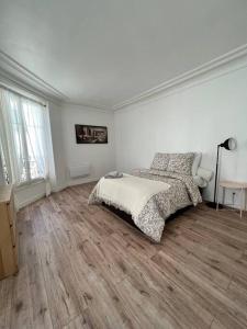 una camera bianca con letto e pavimento in legno di Cosy appartement entre Paris et Disneyland a Le Perreux-sur-Marne