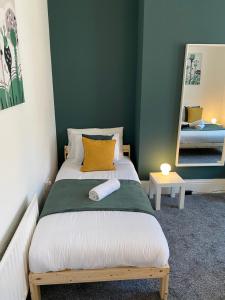 um quarto com uma cama com uma almofada amarela e um espelho em Kitchener - Wonderful 2-Bedroom Apt Sleeps 5 Free Parking Free WiFi em Gateshead