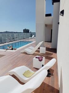 balcón con muebles blancos y piscina en Crazy Hit Tandil en Tandil