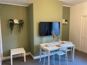 蓋茲黑德的住宿－Kitchener - Wonderful 2-Bedroom Apt Sleeps 5 Free Parking Free WiFi，一张带椅子的白色桌子和墙上的电视