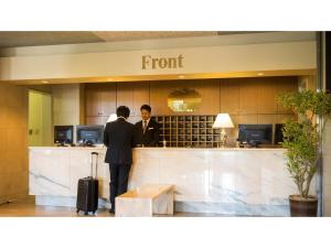 due uomini in piedi al bancone di un hotel di Hotel Areaone Hiroshima Wing - Vacation STAY 62250v a Higashihiroshima Altre 88 foto