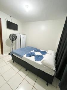 a bedroom with a bed with blue sheets and a fan at Hotel Brasil Anapolis Goias in Anápolis