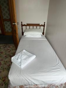 a bed with white sheets and a pillow on it at Club Hotel Pahiatua in Pahiatua +3 photos