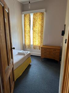 a bedroom with a bed and a window with curtains at Club Hotel Pahiatua in Pahiatua