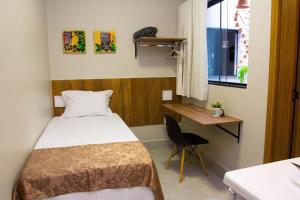 um pequeno quarto com uma cama e uma secretária em Fiori Suítes em Goiânia