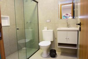 uma casa de banho com um WC e uma cabina de duche em vidro. em Fiori Suítes em Goiânia