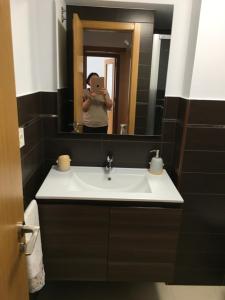 una mujer tomando una foto de un lavabo de baño en Alquiler de piso nuevo, en Burela de Cabo
