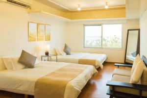 um quarto de hotel com duas camas e um sofá em Seacore Villa - Vacation STAY 14248 em Ishigaki