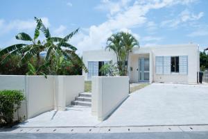 une maison blanche avec une clôture et des palmiers dans l'établissement MILLEFY's HOUSE - Vacation STAY 14247, à Ishigaki
