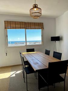 Una mesa de comedor con sillas y una gran ventana. en Skøn lejlighed med havudsigt og tæt på stranden, en Torreguadiaro