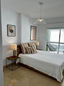 Un dormitorio con una cama grande y una ventana grande. en Skøn lejlighed med havudsigt og tæt på stranden, en Torreguadiaro