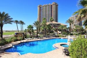 a swimming pool with palm trees and a tall building at Portofino Island Resort Tower 2-703 in Pensacola Beach
