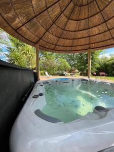 a hot tub with an umbrella on top of it at Gîte du Placello, piscine jacuzzi et sauna in Quistinic