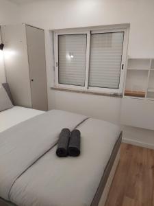 阿爾馬達的住宿－Lisbon South Bay Rooms，卧室内的一张带两张黑色拖鞋的床