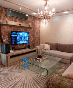 Big, stylish and modern apartment with hot tub في طنجة: غرفة معيشة مع أريكة وتلفزيون