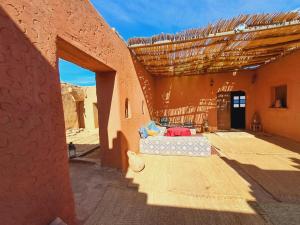 a building in the desert with a bed in the courtyard at LA PETITE MAISON DU LAC IRIKI in Foum Zguid