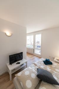 een witte slaapkamer met een groot bed en een flatscreen-tv bij LE DAUPHIN - Place parking privée gratuit - WIFI et TV in Saint-Étienne