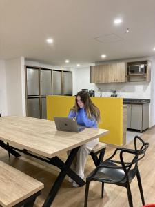 a woman sitting at a table with a laptop at UhaUs Coliving 302 - Apto 12 habitaciones in Manizales