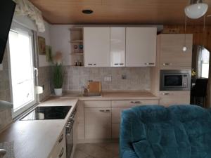 a kitchen with white cabinets and a blue chair at Spreewaldhäuser Golinski mit Kamin am Neuendorfer See in Alt Schadow