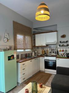 a kitchen with white cabinets and a blue refrigerator at Daphné Village House - close to Methana & Poros in Methana