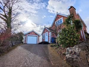 a house with a white garage and a driveway at Unbeatable Llanberis Location, Detached with Parking, Snowdon Views. in Llanberis