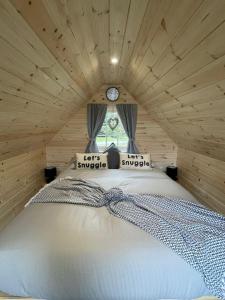 a bed in a small room with a clock on the window at Wildflower Meadow Cabins in Whitington