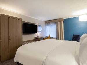 a hotel room with a bed and a flat screen tv at Holiday Inn Express & Suites Greensboro - I-40 atWendover, an IHG Hotel in Greensboro