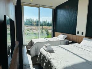 2 Betten in einem Zimmer mit einem großen Fenster in der Unterkunft Cubos de Chacras in Ciudad Lujan de Cuyo