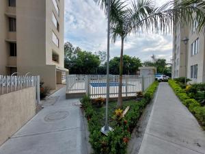 a sidewalk with a fence and palm trees next to a building at Apartamento Barlovento Piso 5 Vista a la Piscina in Girardot