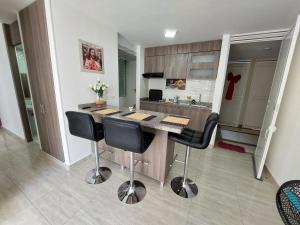 a kitchen with a island with black bar stools at Apartamento Barlovento Piso 5 Vista a la Piscina in Girardot