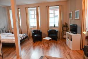 a bedroom with a bed and two chairs and a television at Haus Weihertor in Traben-Trarbach