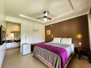 a bedroom with a large bed with a ceiling fan at Pousada Camarás in Alto Paraíso de Goiás