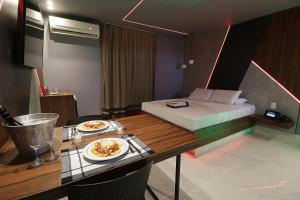 a room with a bed and a table with a plate of food at Exótico Prime Motel RP in Ribeirão Preto