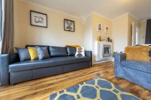 sala de estar con sofá negro y silla azul en Pierocks Carver Entire house, Hot tub & WIFI en High Wycombe