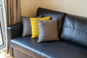 - un canapé en cuir noir avec trois oreillers dans l'établissement Pierocks Carver Entire house, Hot tub & WIFI, à High Wycombe