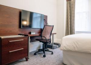 Zimmer mit einem Schreibtisch, einem TV und einem Stuhl in der Unterkunft Club Quarters Hotel Trafalgar Square, London in London