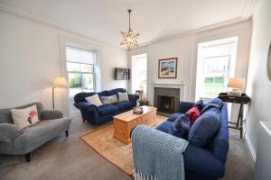 a living room with blue couches and a fireplace at Longhill Farmhouse in Whithorn
