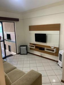 uma sala de estar com um sofá e uma televisão de ecrã plano em Apartamento vista mar com 3 quartos e churrasqueira em Itapema