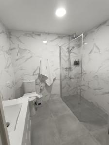 uma casa de banho branca com um chuveiro e um WC. em Hotel Posada del Mar em Suances