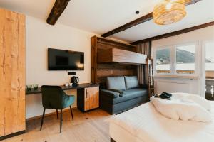 a room with a bed and a couch and a chair at Dorfhotel Glücksschmiede in Saalbach Hinterglemm