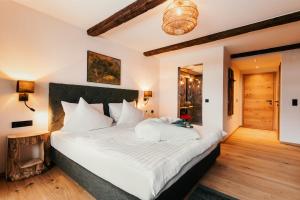 1 dormitorio con 1 cama grande con sábanas blancas en Dorfhotel Glücksschmiede, en Saalbach Hinterglemm